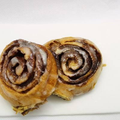Dos rollos de canela glaseados servidos en plato blanco